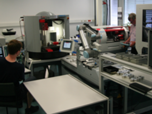 Zwei Mitarbeiter bedienen Fräs- und Drehmaschine im Labor Trainingsfabrik 4.0 beim Einrichten